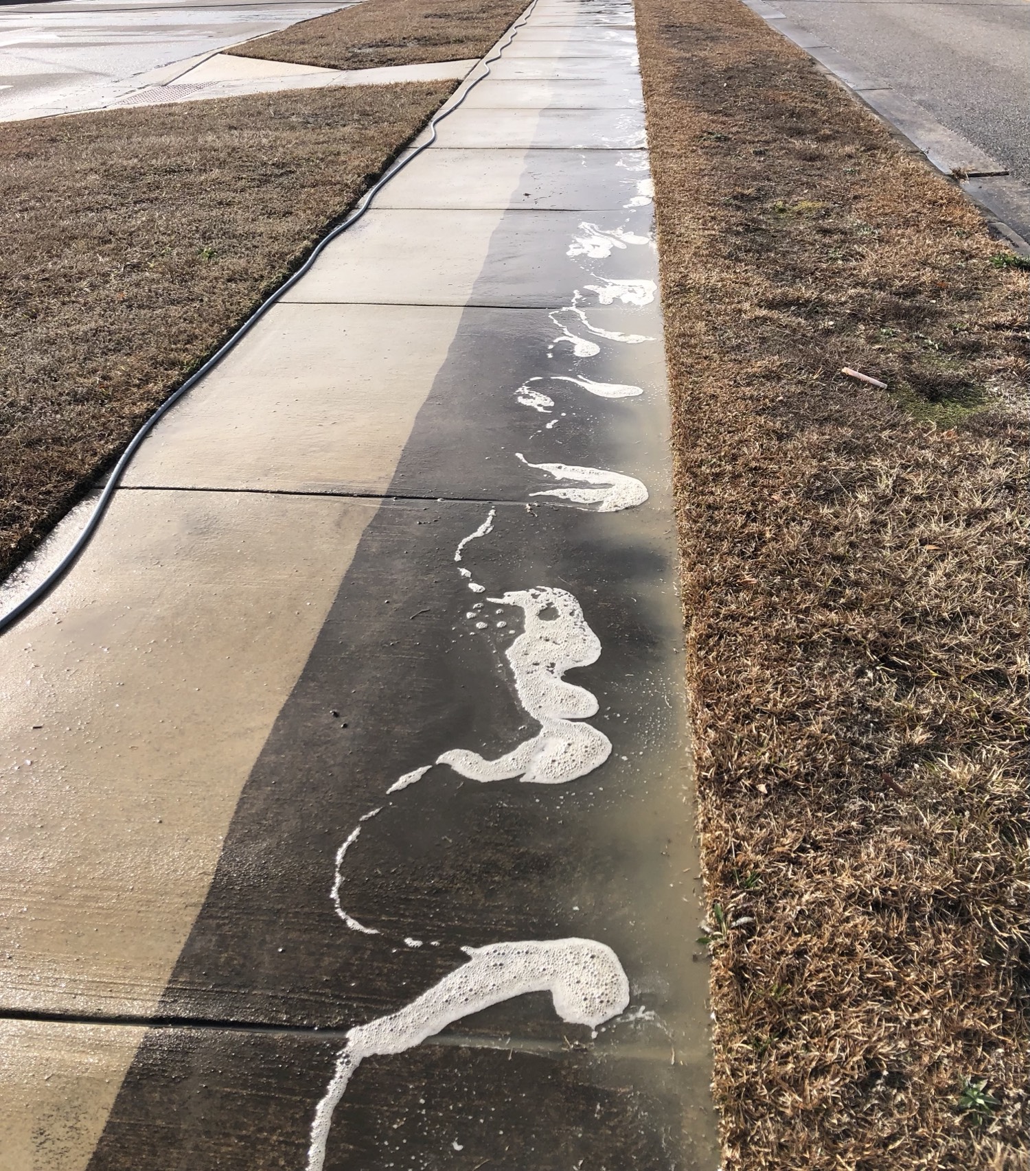 Sidewalk half cleaned, half still stained